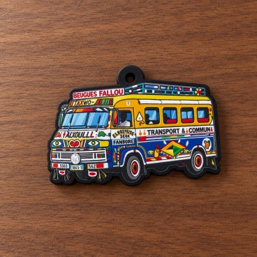 Colorful PVC patch of a bus with vibrant decorations and text, on a wooden surface.