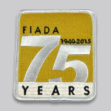Patch commemorating 75 years with large white '75' on yellow background, labeled 'FIADA 1940-2015'.