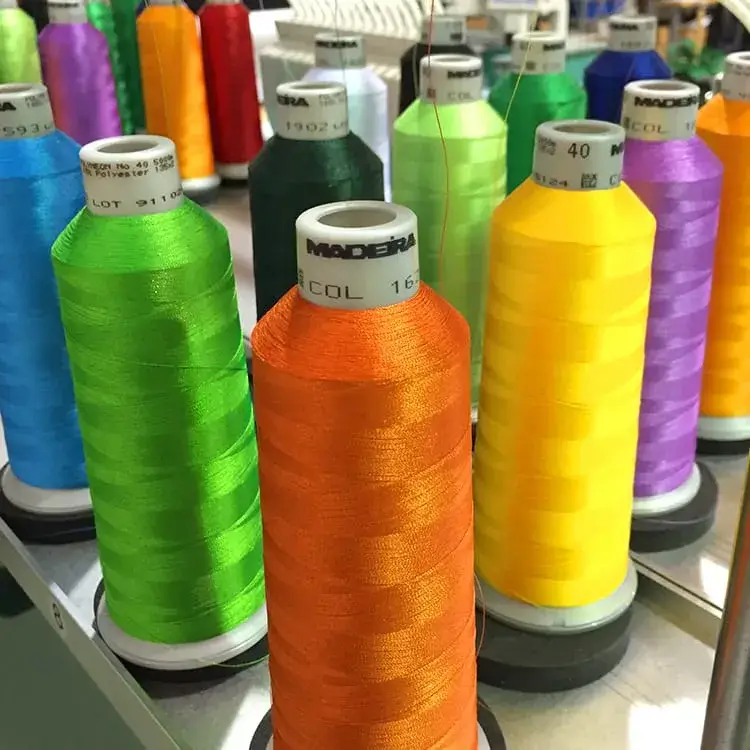 Spools of bright embroidery thread in green, orange, yellow, blue, and purple on an embroidery machine