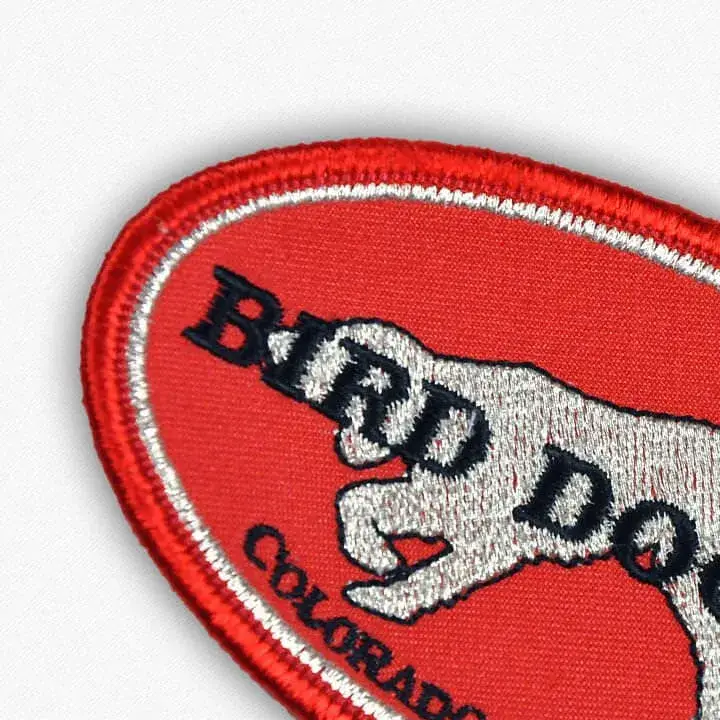 Red patch with a dog stitched in shimmering silver metallic thread